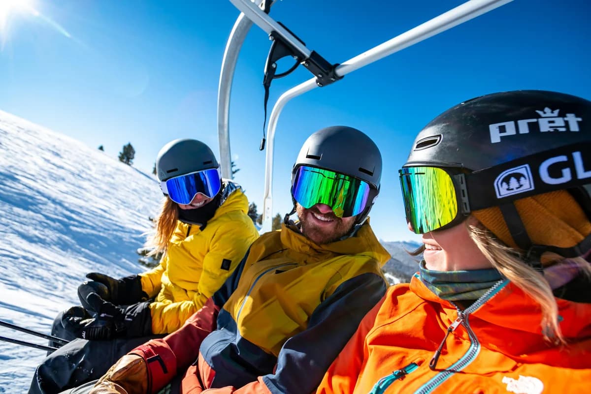 Tres esquiadores sonrientes en un telesilla, al sol