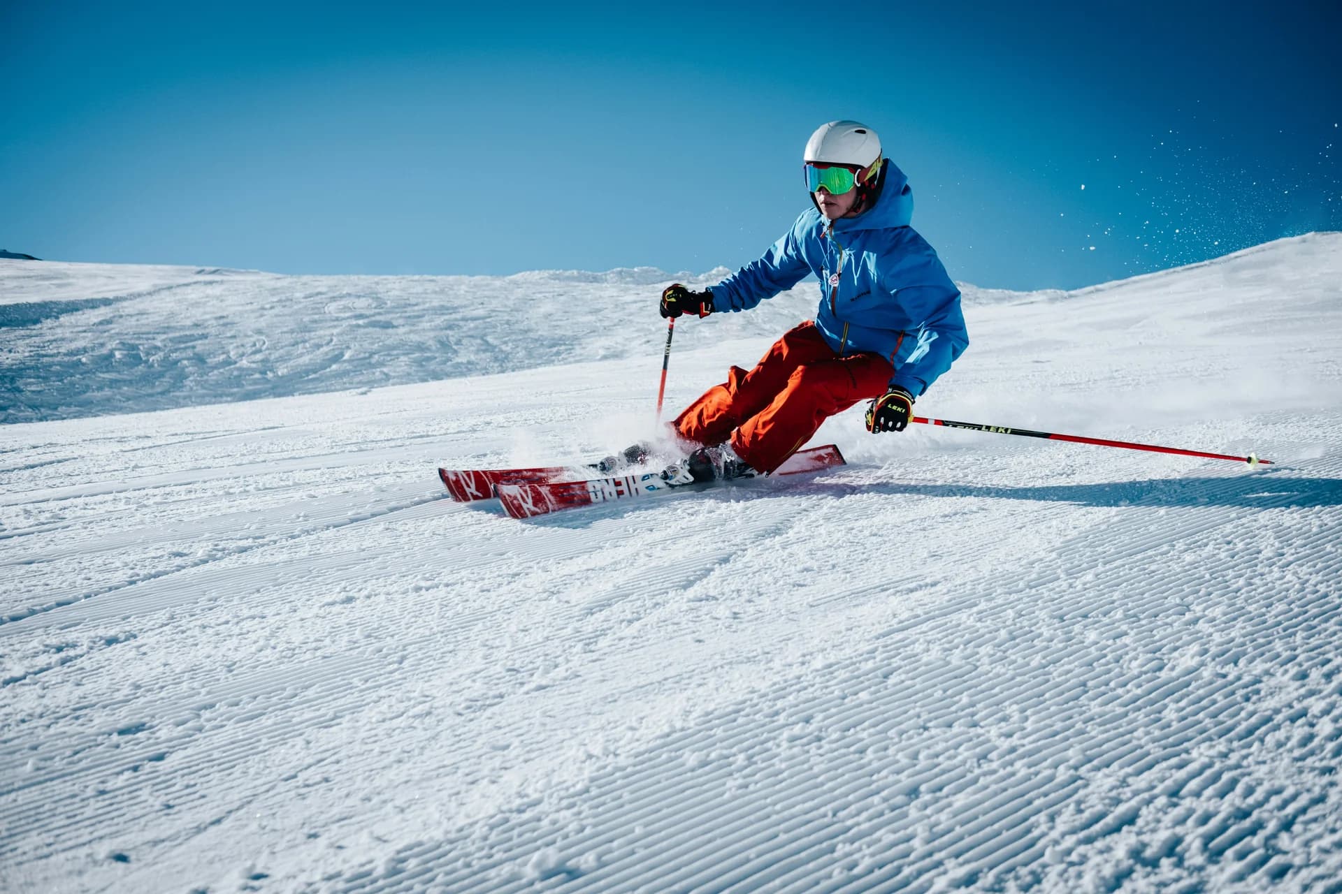 Skieur sur une piste damée, sous un ciel bleu
